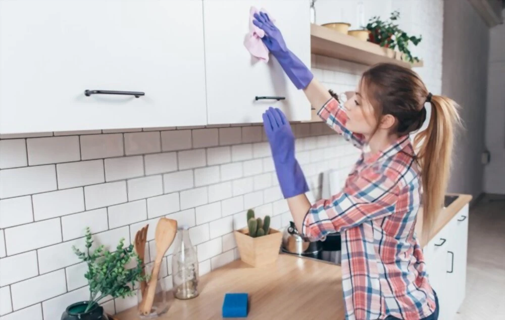 Young woman cleaning the cabinets in the kitchen