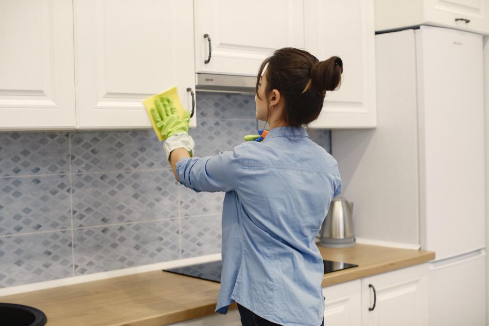 Woman wiping kitchen cabinets 